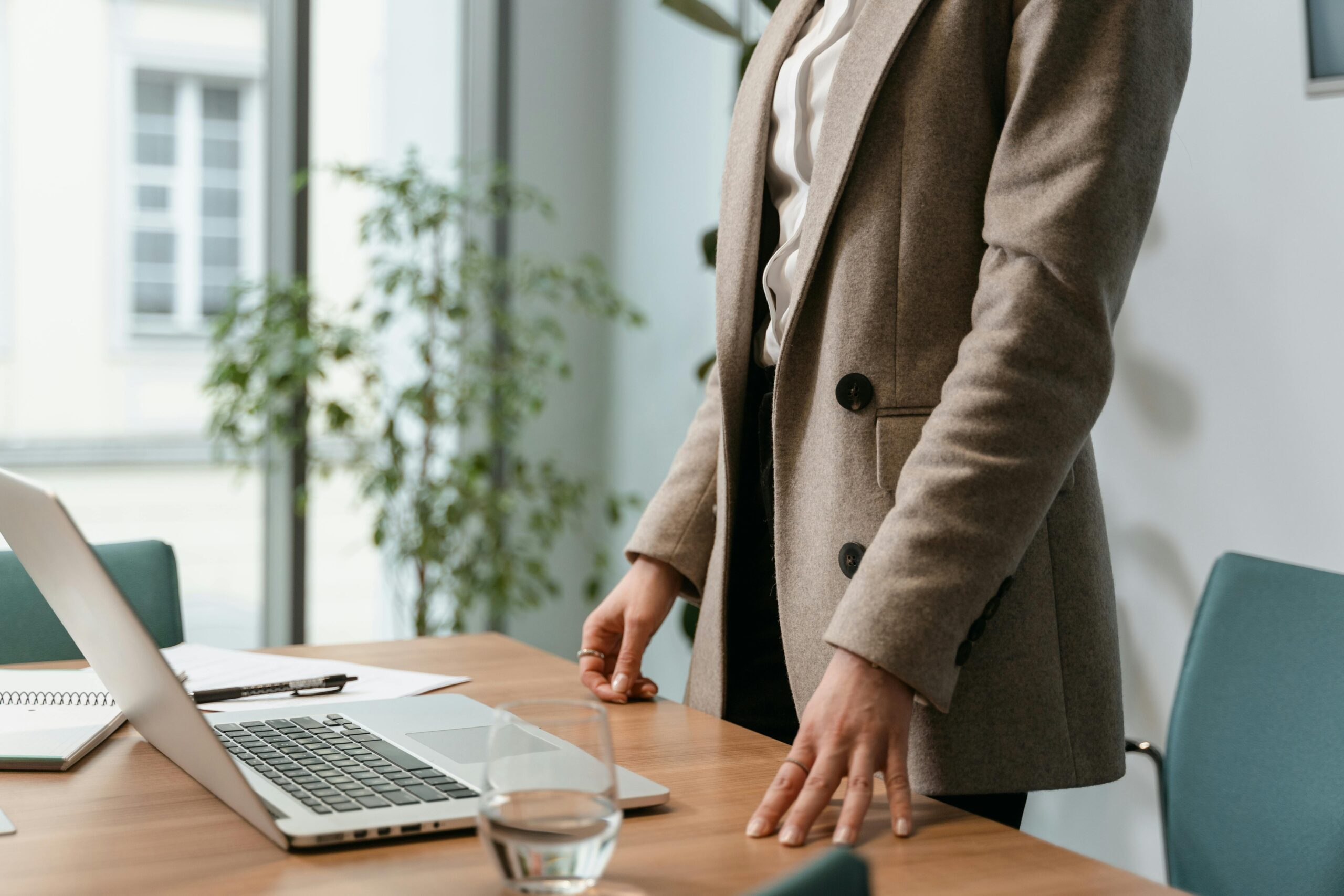 A confident business owner smiling while working on a laptop in a stylish office space.