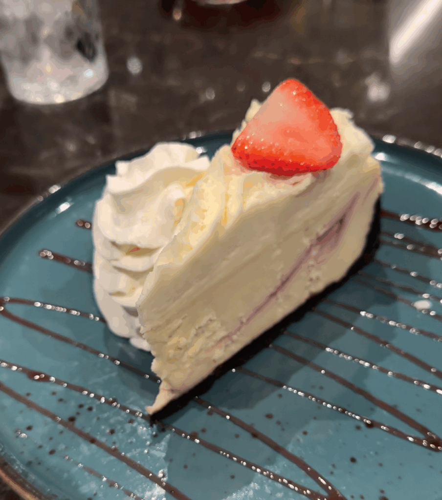 White chocolate raspberry cheesecake from Baton Rouge Moncton topped with raspberry swirl and served on a white plate.