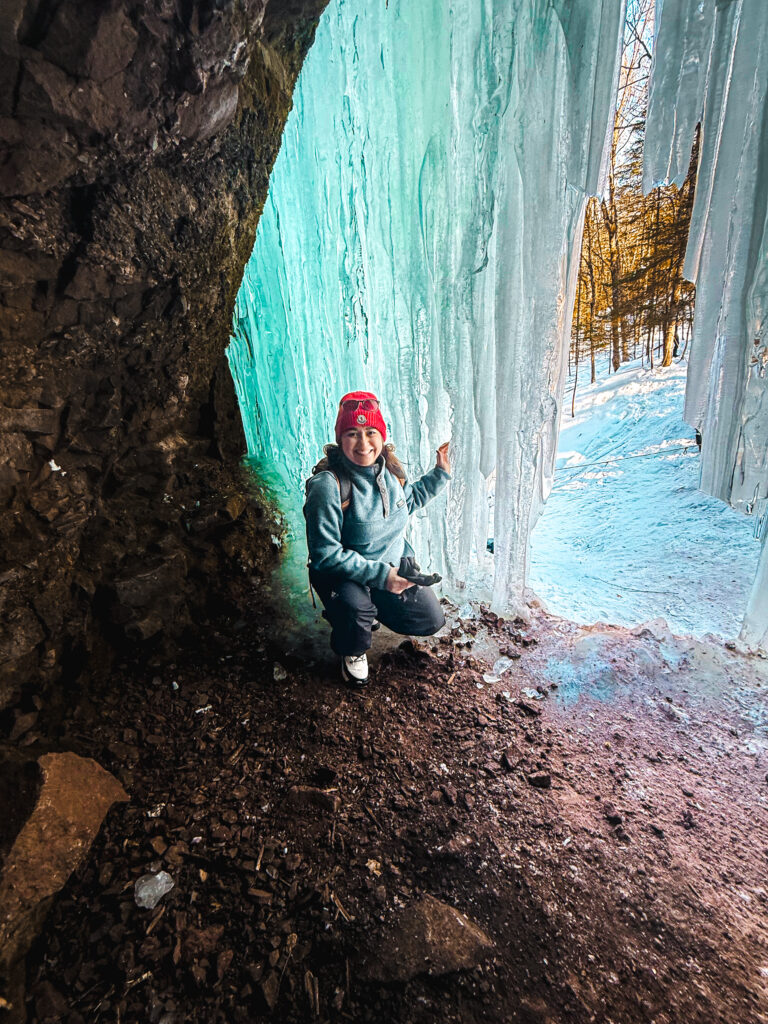 Woman inside Midland Ice Caves touching the frozen ice wall in New Brunswick