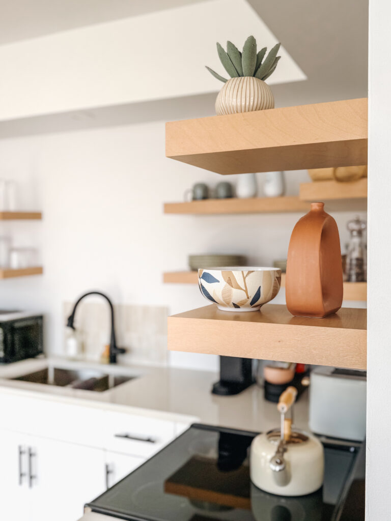 Styled open kitchen shelves inside a Glamping Aboiteau unit with a succulent ceramic bowl terracotta vase and tea kettle