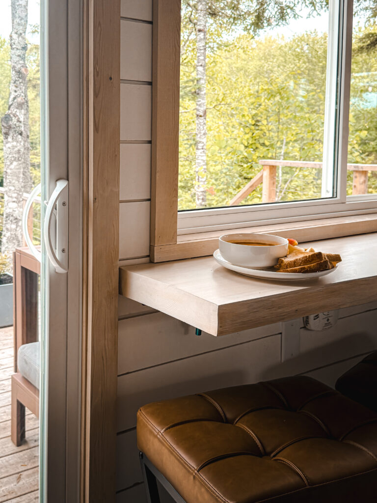 Bowl of soup and toast on the fold-down window ledge at Eagles Nest cabin, with birch trees visible outside