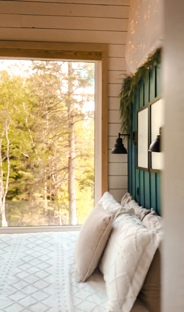 Eagles Nest bedroom with a teal board-and-batten headboard wall and a large window looking out at the forest