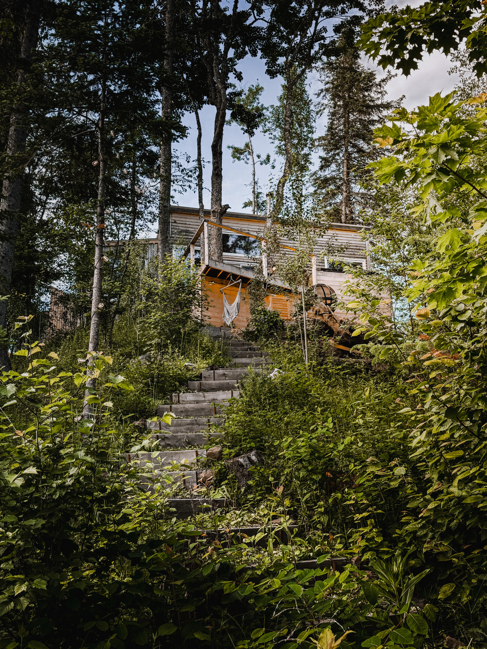 Eagles Nest cabin deck with string lights glowing at dusk above the river in Saint-Marie-de-Kent, New Brunswick